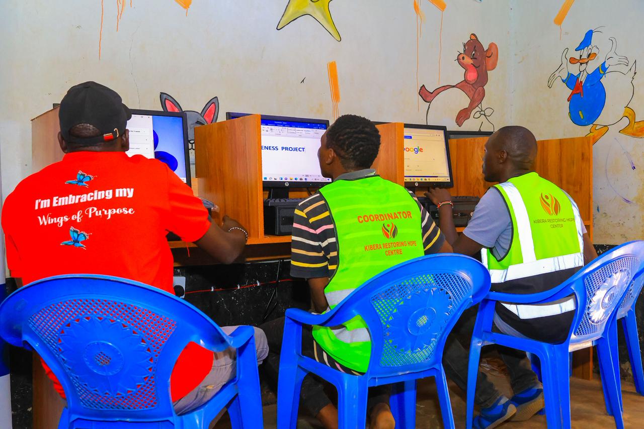 From right, Emmanuel Sananka, helping students to log into the computers during the distribution of computers to Kibera Restoration Hope Youth Centre. Nairobi
